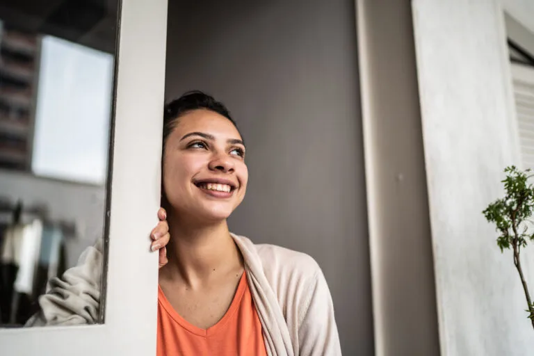 Contemplative teenage girl looking through window at home