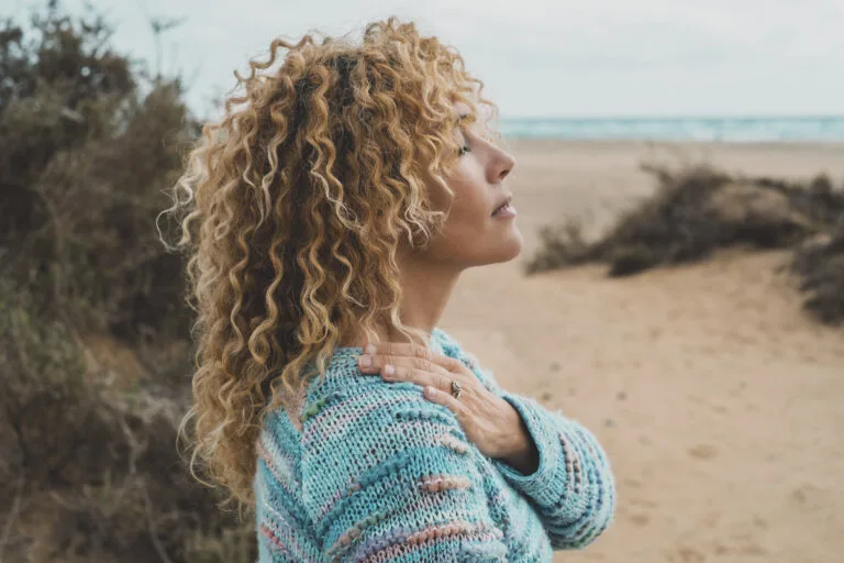 One woman enjoy inner balance and meditation leisure outdoor activity alone feeling nature hugging herself at the beach. Side portrait of zen lifestyle and happiness female people. Closed eyes love